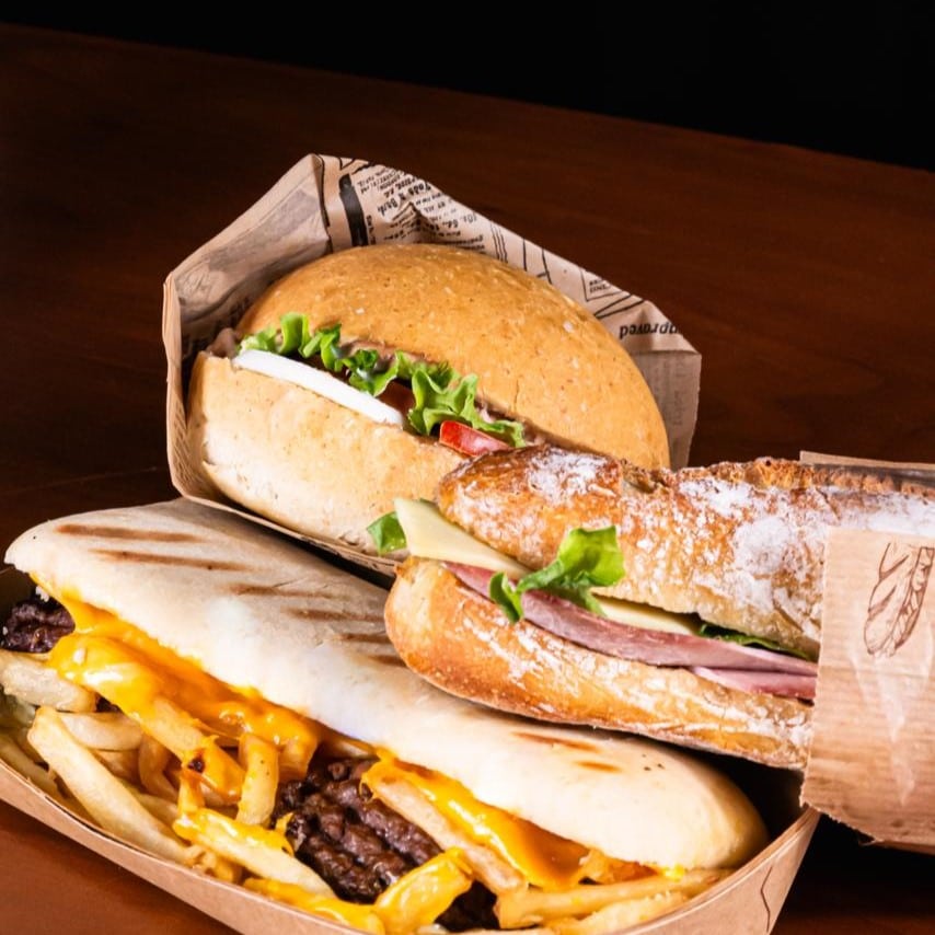 Empilement appétissant de trois snacks populaires à l'épi d'or du chablais : l'américain, le sandwich jambon beurre et le burger.